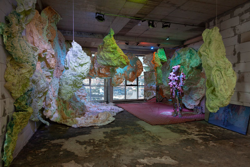 A derelict room with an installation of colourful, cloud-like sculptures